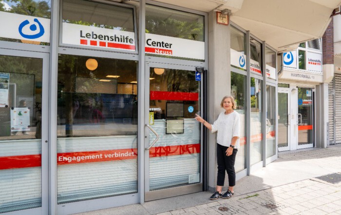 Eine Frau steht vor dem Lebenshilfe Center und zeigt auf das Refill Logo an der Eingangstür.