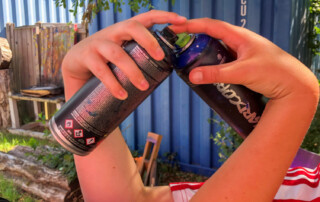 Zwei Kinder formen mit ihren Armen und Spraydosen ein Herz.