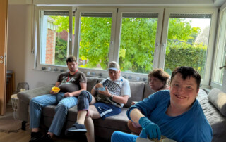 Mehrere Bewohner sitzen auf der Couch und schauen den Film an.