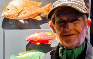 Eine Frau vor 3 Fischstatuen.