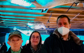 3 Personen vor einem Wal.