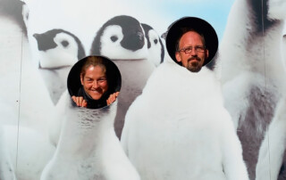 Zwei Personen schauen durch ein Loch in einer Fotoleinwand.