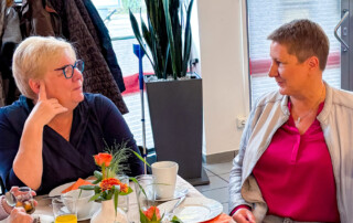 Zwei Frauen unterhalten sich am Tisch.