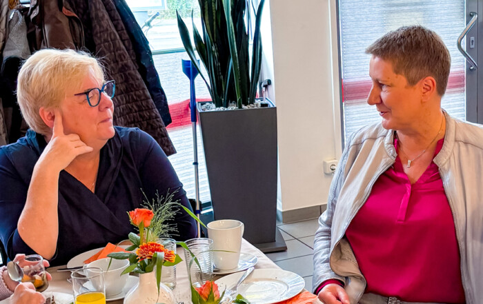 Zwei Frauen unterhalten sich am Tisch.