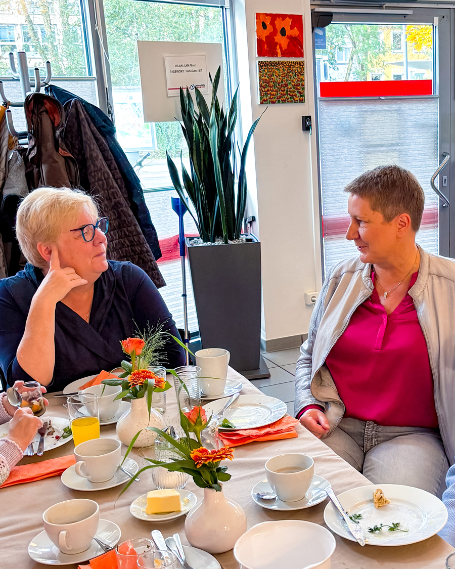 Zwei Frauen unterhalten sich am Tisch.