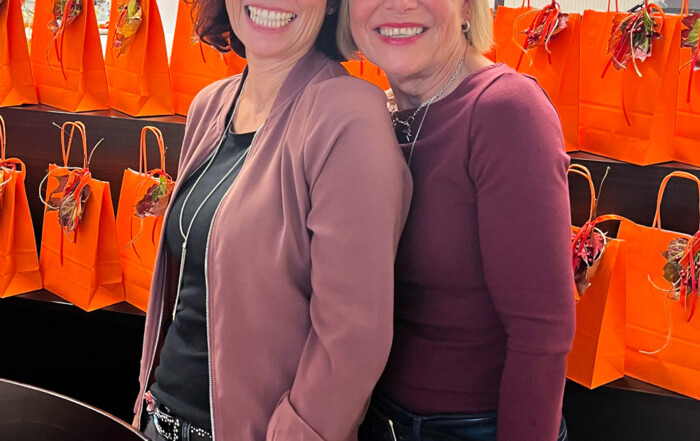 Zwei Frauen lächeln in die Kamera.