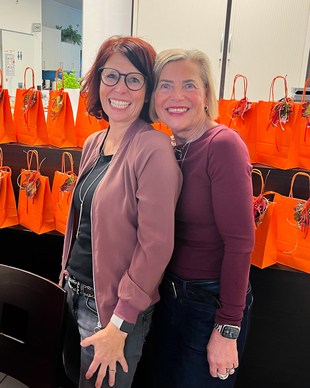 Zwei Frauen lächeln in die Kamera.