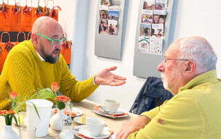 Zwei Männer unterhalte sich am Tisch.