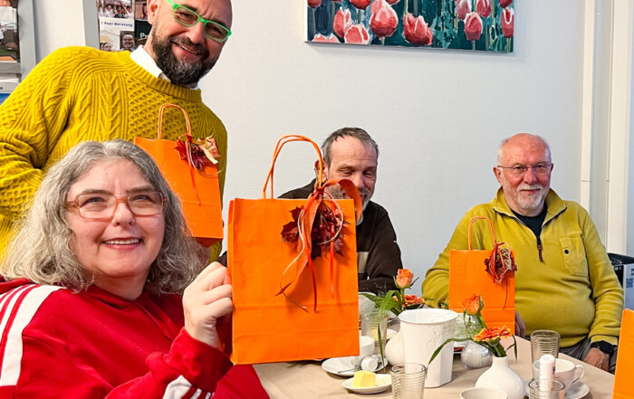 Eine Gruppe am Tisch mit orangen Tüten.