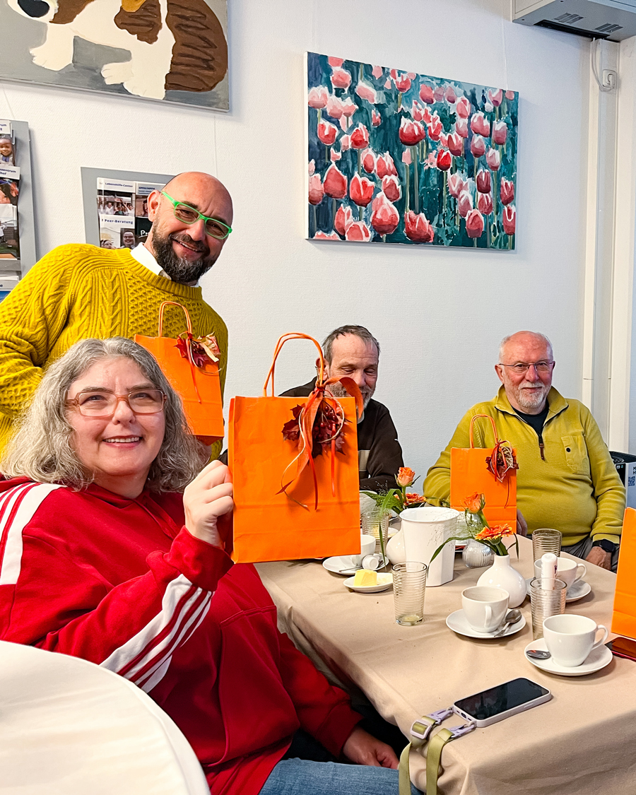 Eine Gruppe am Tisch mit orangen Tüten.