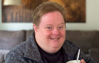 Frau lächelt mit Tasse in der Hand.