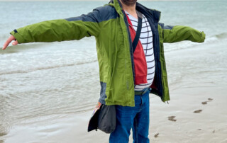 Ein Mann steht im Wind am Meer.