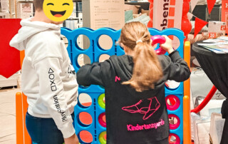 Zwei Kinder spielen ein übergroßes Vier-Gewinnt Spiel.