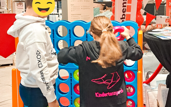 Zwei Kinder spielen ein übergroßes Vier-Gewinnt Spiel.