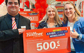 Drei Personen halten den Hauptgewinn in die Kamera und zwar ein Gutschein in Höhe von 500€.