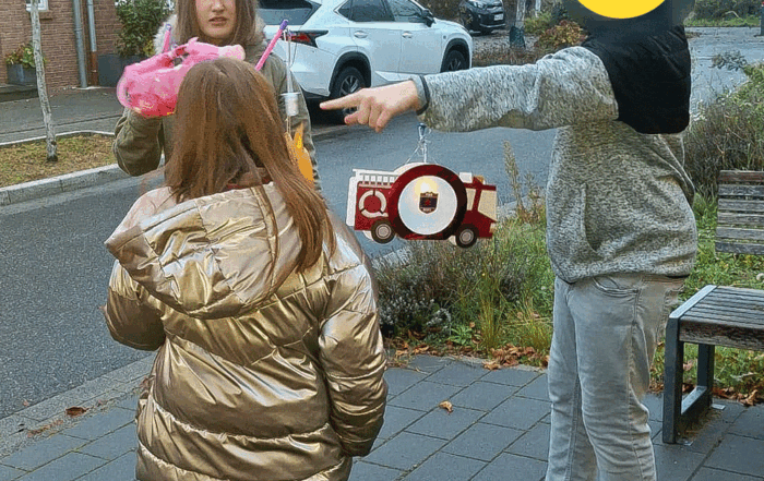 Drei Kinder stehen zusammen und begleiten den Umzug mit ihren Laternen.