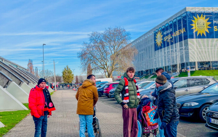 Die Bewohner und Bewohnerinnen stehen zusammen vor dem Stadion.