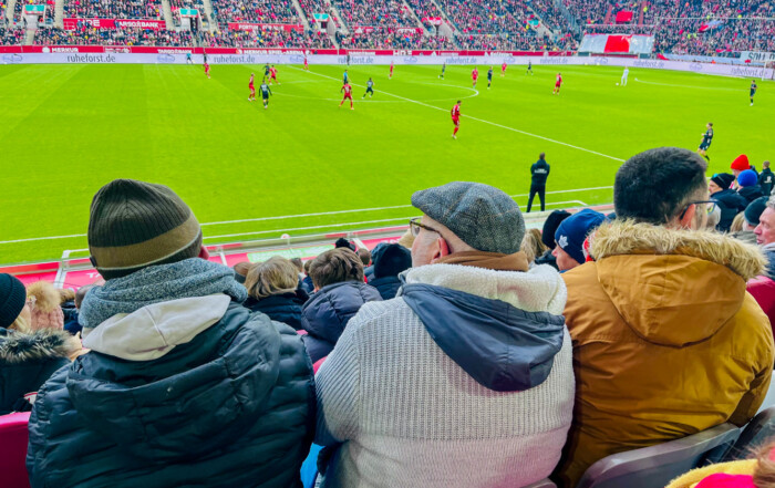 Drei Bewohner schauen sich das Spiel an.