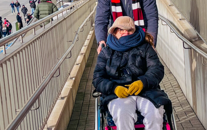 Ein Betreuer und eine Bewohnerin sind auf dem Weg ins Stadion.