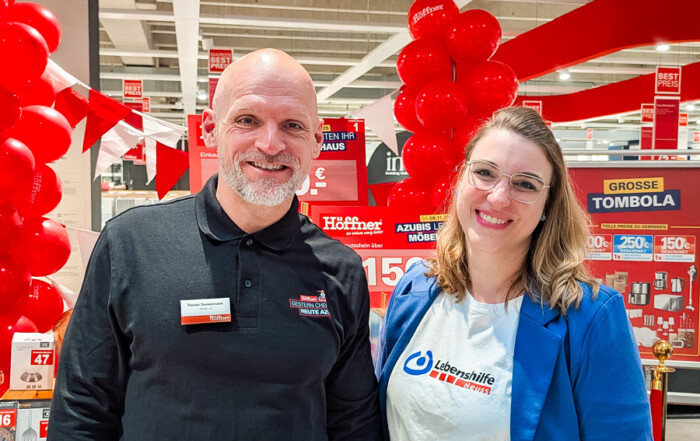 Eine Mann von dem Möbelhaus und eine Frau der Lebenshilfe stehen zusammen für ein Foto.