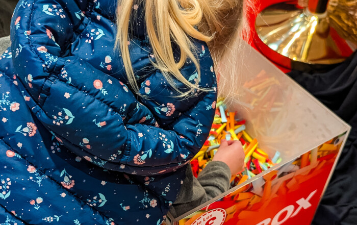 Ein kleines Mädchen greift in die Losbox.