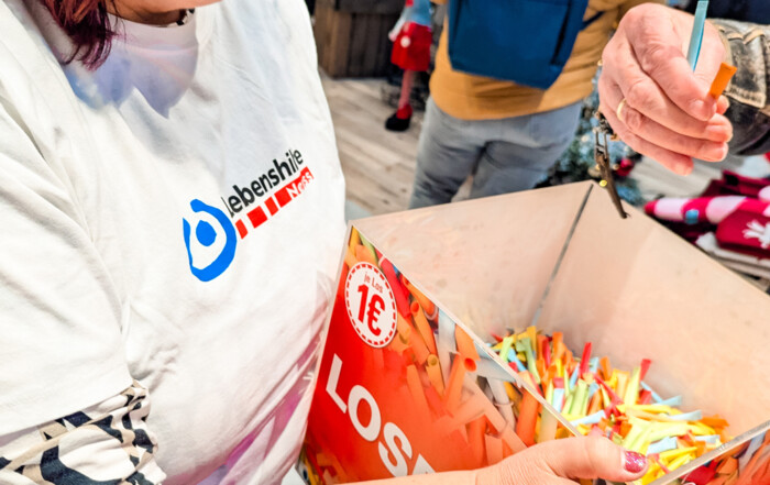 Eine Frau hält die Box mit den Losen in der Hand.