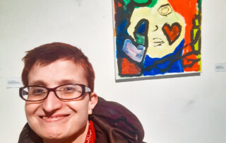 Eine Teilnehmerin steht vor ihrem ausgestellten Bild.