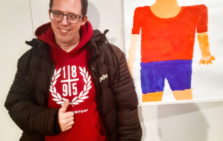 Eine Teilnehmer steht vor ihrem ausgestellten Bild.