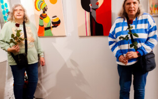 Zwei Teilnehmerinnen stehen vor Ihren ausgestellten Bildern.