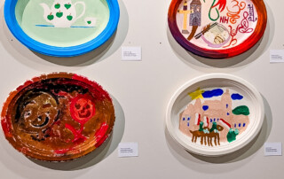 Vier Kunstwerke hängen an der Wand in der Ausstellung.