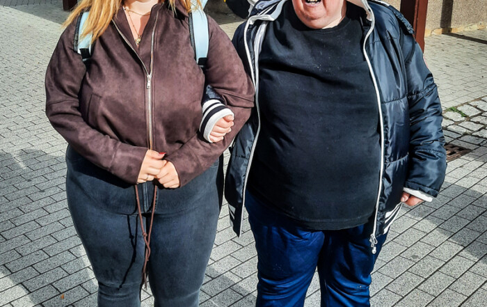 Eine Bewohnerin und eine Betreuerin stehen zusammen für ein Foto.