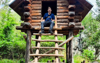 Ein Bewohner sitzt in einem Baumhaus und posiert für ein Foto.