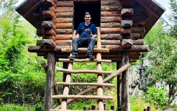 Ein Bewohner sitzt in einem Baumhaus und posiert für ein Foto.