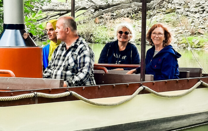 Mehrere Bewohnende fahren mit einem Boot über ein Teich im Zoo.