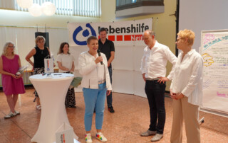 Gesine Eschenburg steht mit mehreren Personen am Podium und redet ins Mikrofon.