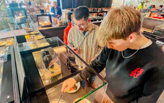 Bewohner und Betreuer schauen sich das Buffet an und wählen ihr Essen.