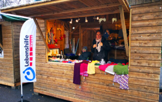 Eine Frau steht mit ihrem Kind im Stand und lächelt in die Kamera.
