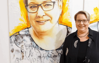 Ein Bild von Katrin Zaum vor ihrem ausgehängten Portrait