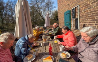 Die ganze Gruppe sitzt zusammen bei Kaffee und Kuchen.