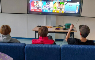 Drei Jungs sitzen auf der Couch und zocken.