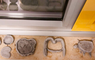 Verschiedene Figuren aus Knete auf einer Fensterbank ausgelegt.