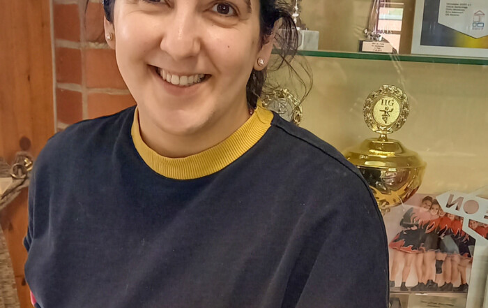 Eine Frau hält einen Teller mit einer Waffel drauf in die Kamera und lächelt.