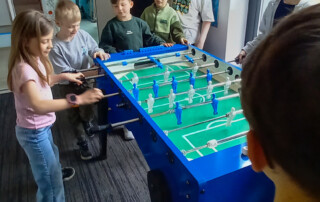 mehrere Kinder spielen zusammen Kicker.