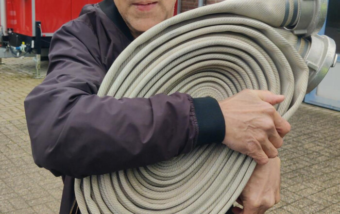 Ein Mann aus den Offenen Hilfen hält einen Wasser-Schlauch.