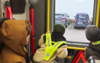Die Kinder schauen aus einem Auto Fenster raus und bestaunen die Feuerwehr-Autos