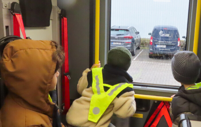 Die Kinder schauen aus einem Auto Fenster raus und bestaunen die Feuerwehr-Autos