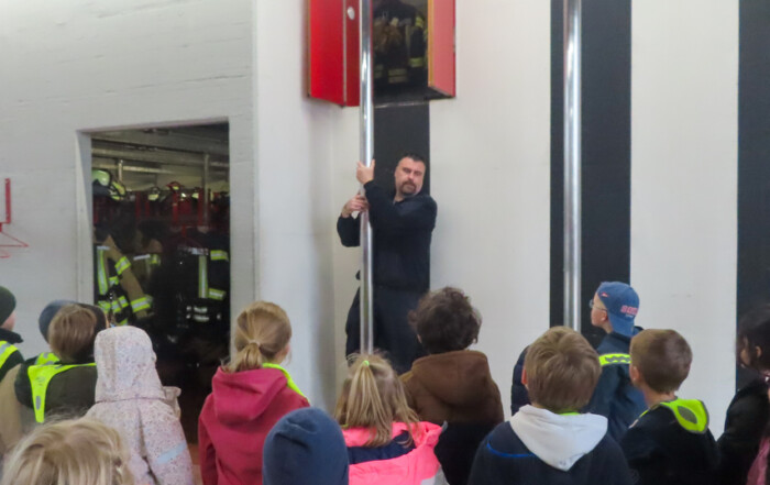 Ein Feuerwehr-Mann erklärt den Kindern etwas.