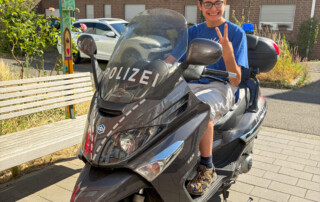Ein Junge sitzt auf einem Polizei-Motorrad.