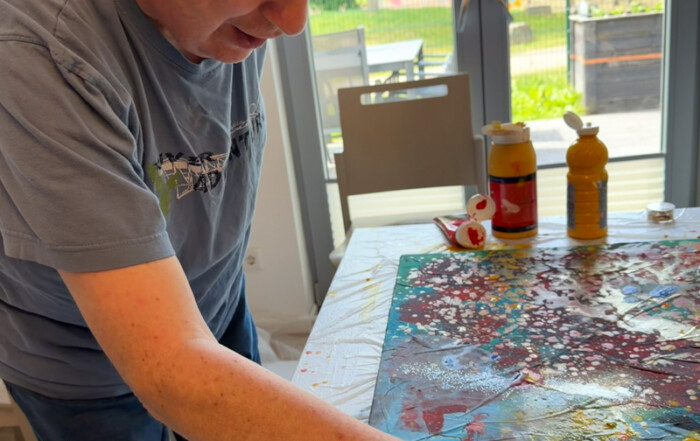 Ein Bewohner malt mit der Hand das Bild.