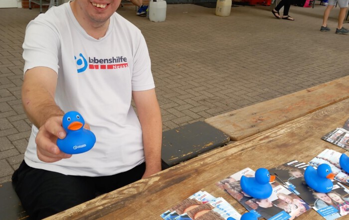 Ein Bewohner hält eine Lebenshilfe Gummi-Ente in die Kamera an unserem Stand bei dem Spendenlauf